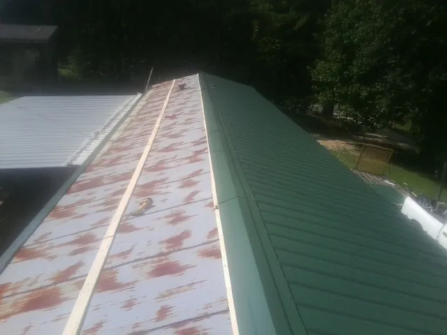 Old rusted panels beside newly installed green metal roofing — Wind Damage Roof Repair by Roofing Brothers in Ridgefield