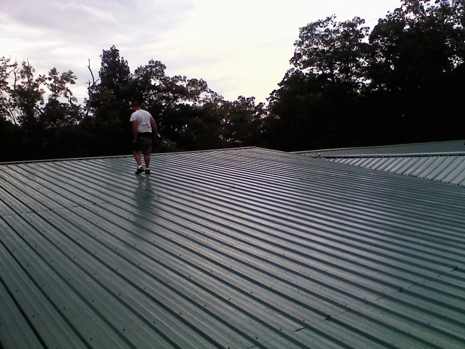 Roofer walking a wide expanse of new green metal roofing in Ridgefield
