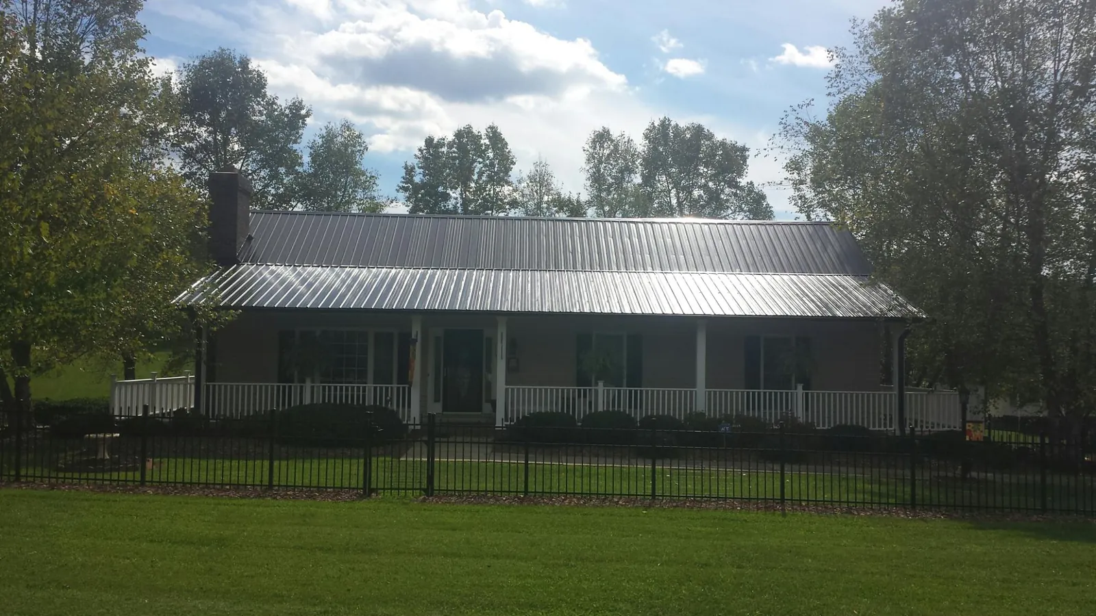 Gray metal roof on a brick ranch with a full width front porch — Gutter Guard Installation work by our crew in Ridgefield